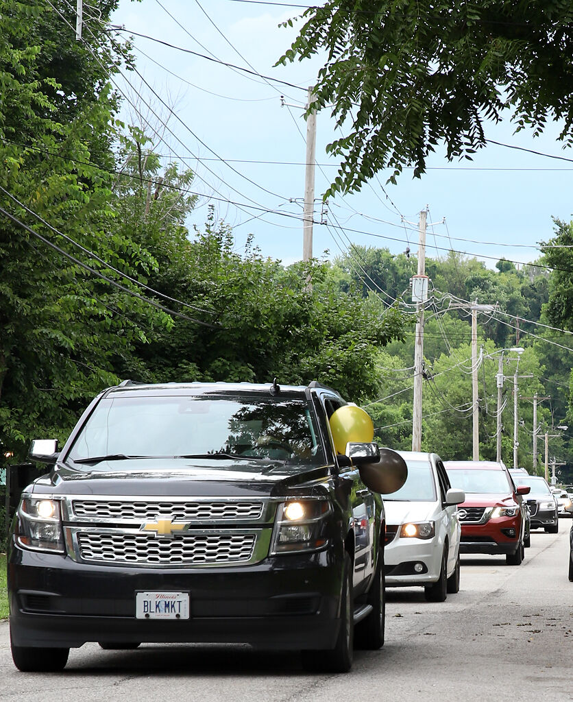 Cars line up and begin to honk their horns at the graduation parade on Saturday